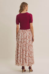 woman wearing a plum short sleeve top and a long floral skirt, seen from the back