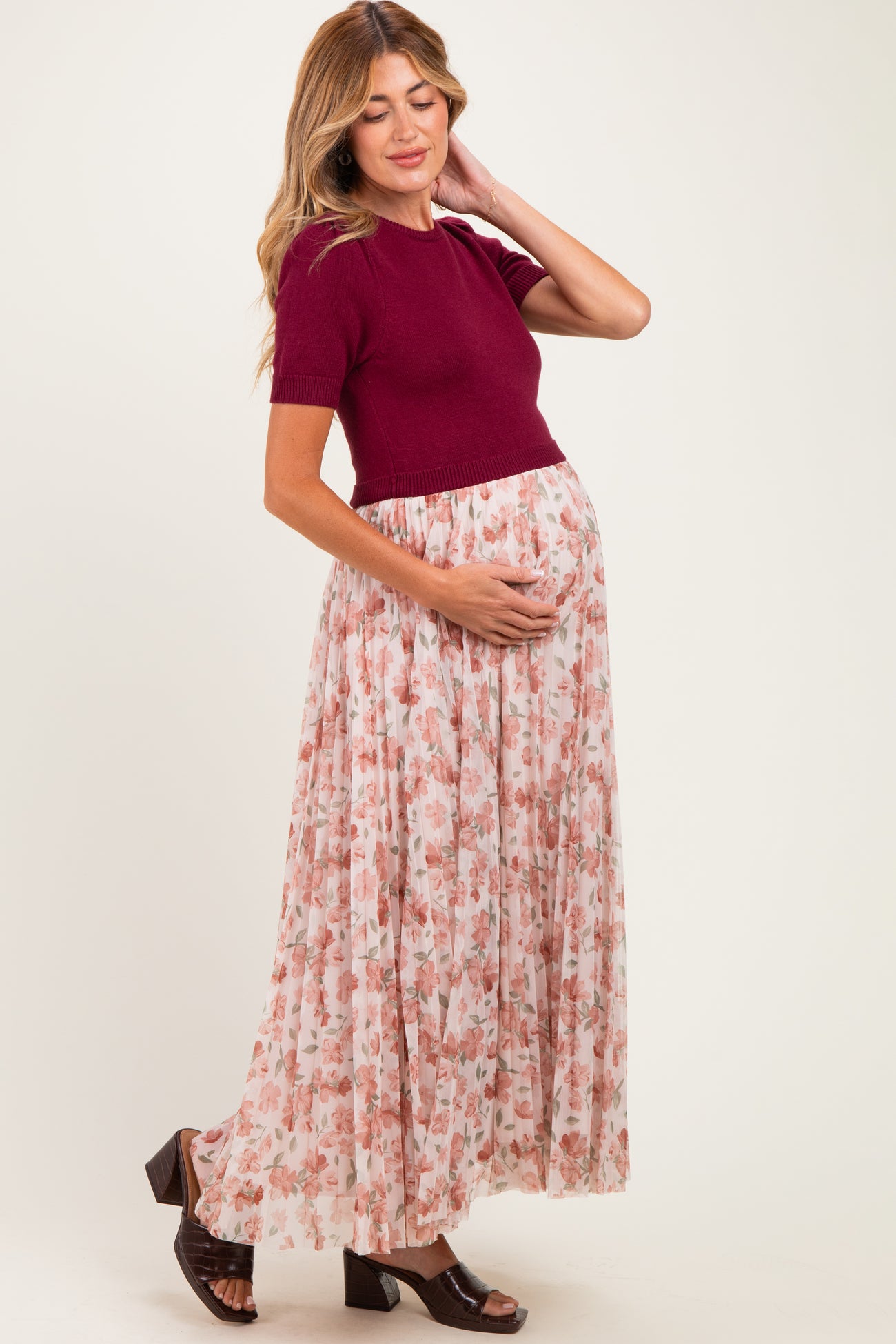woman wearing a burgundy knit shirt and a floral maxi skirt, showing baby bump in this maternity wear outfit
