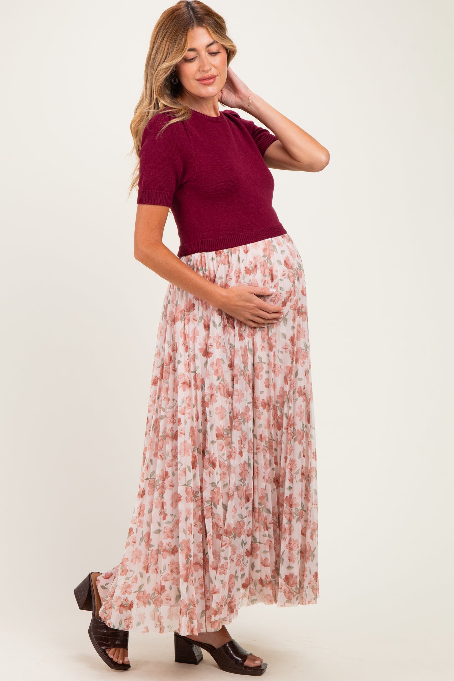 woman wearing a burgundy knit shirt and a floral maxi skirt, showing baby bump in this maternity wear outfit