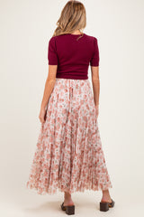 woman wearing a maroon short sleeve top and a flowy pink floral maternity skirt from the back