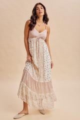 woman wearing a floral print maxi dress with tiered layers in soft pink and white tones, styled with a relaxed fit