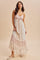 woman wearing a floral print maxi dress with tiered layers in soft pink and white tones, styled with a relaxed fit