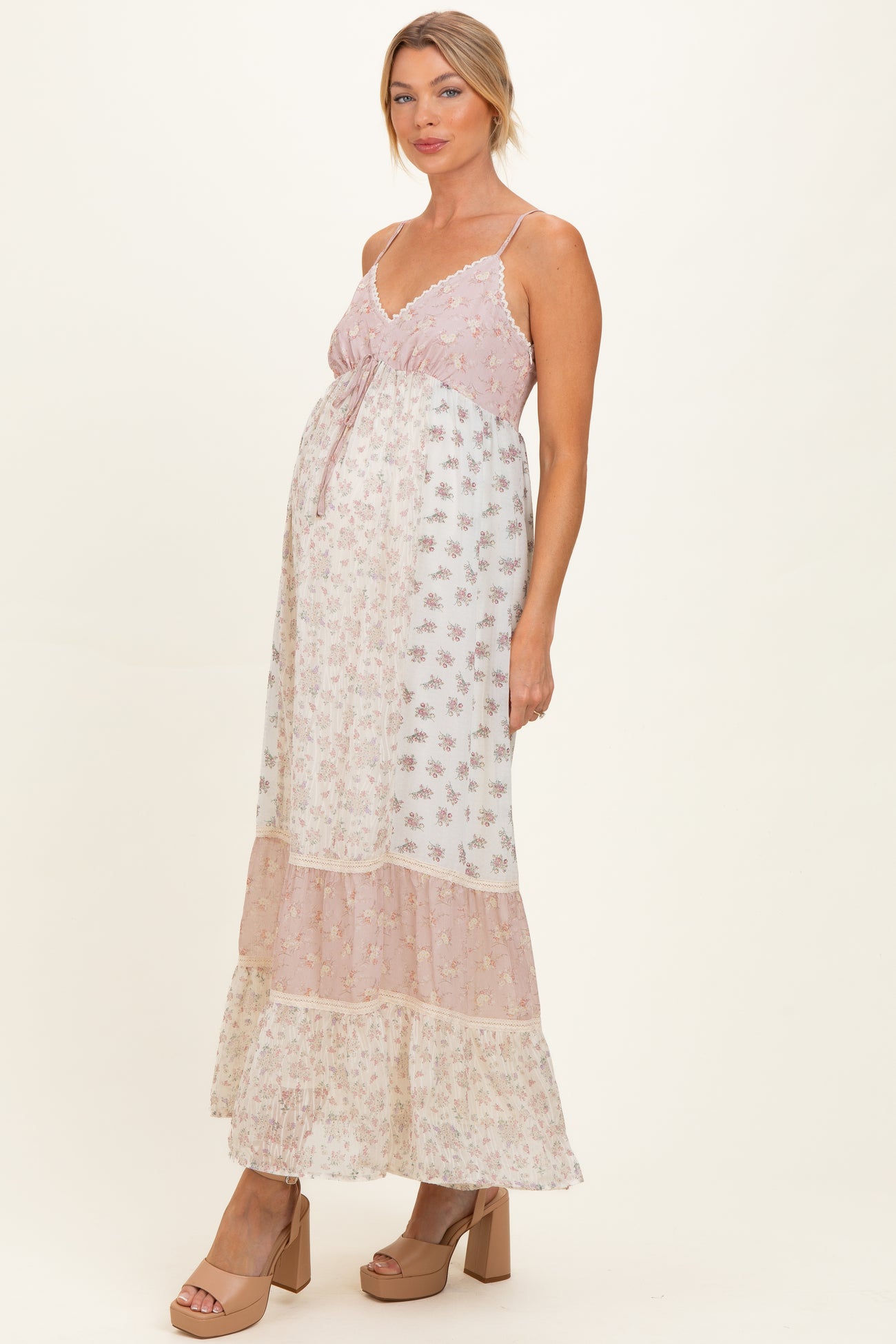 woman wearing a pink and white floral maternity maxi dress with a tiered skirt and a visible baby bump