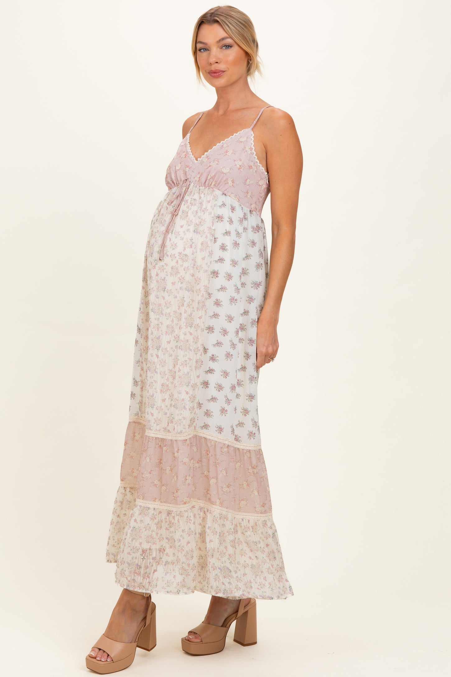 woman wearing a pink and white floral maternity maxi dress with a tiered skirt and a visible baby bump