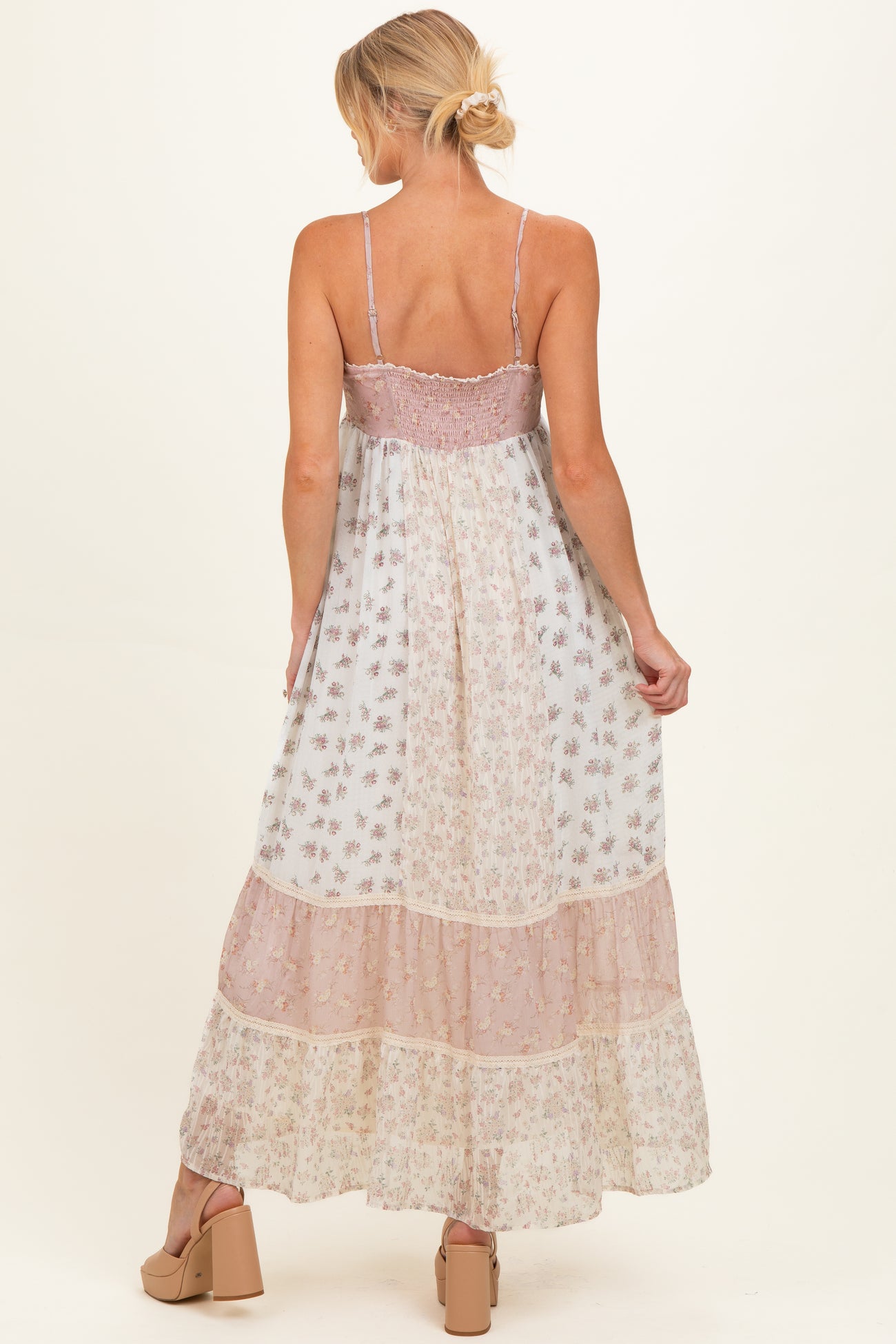woman wearing a flowy floral maternity maxi dress with adjustable straps and tiered layers, showing her back