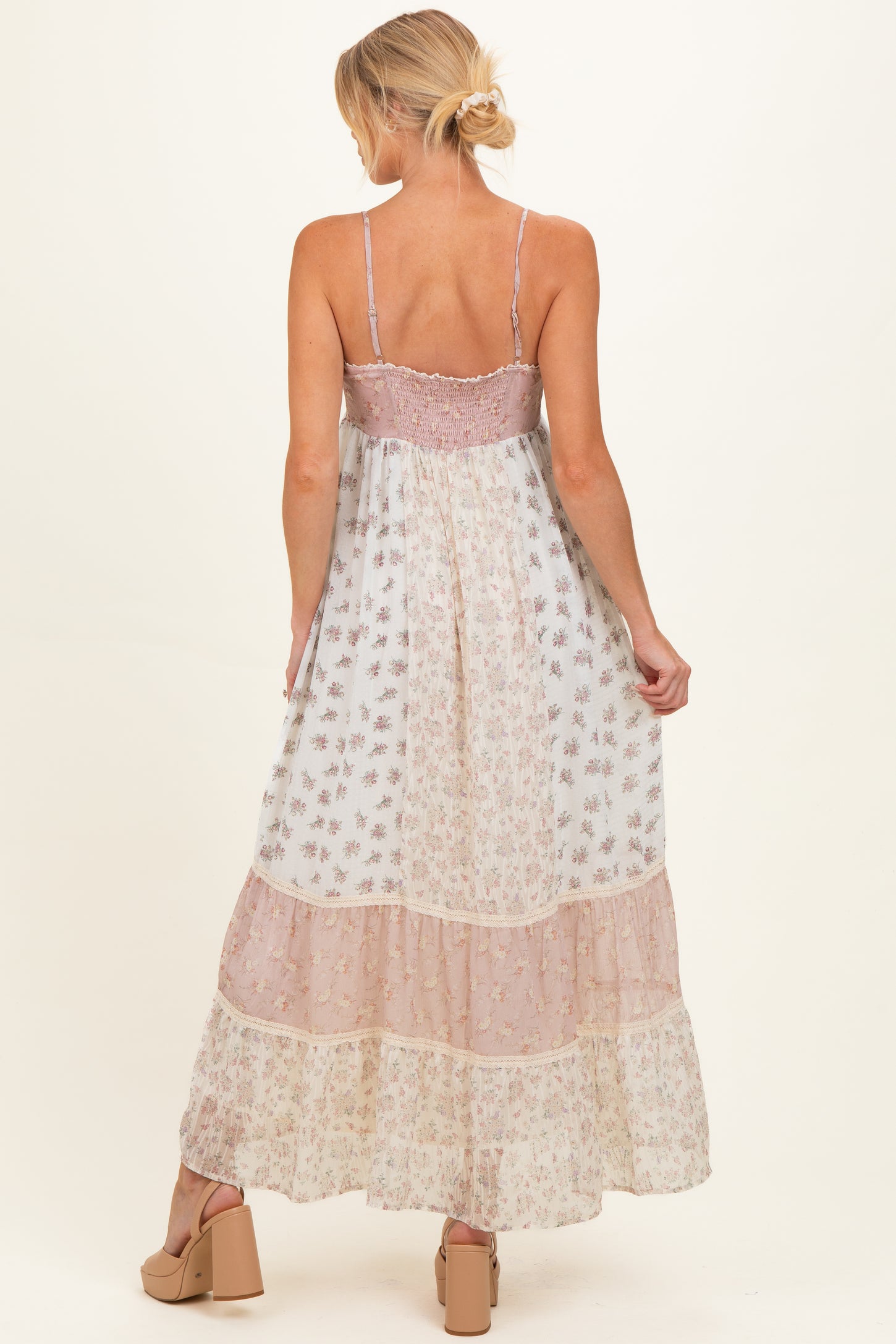 woman wearing a flowy floral maternity maxi dress with adjustable straps and tiered layers, showing her back