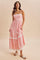 woman wearing a pink floral maxi dress with lace trim and spaghetti straps, standing on a beige background