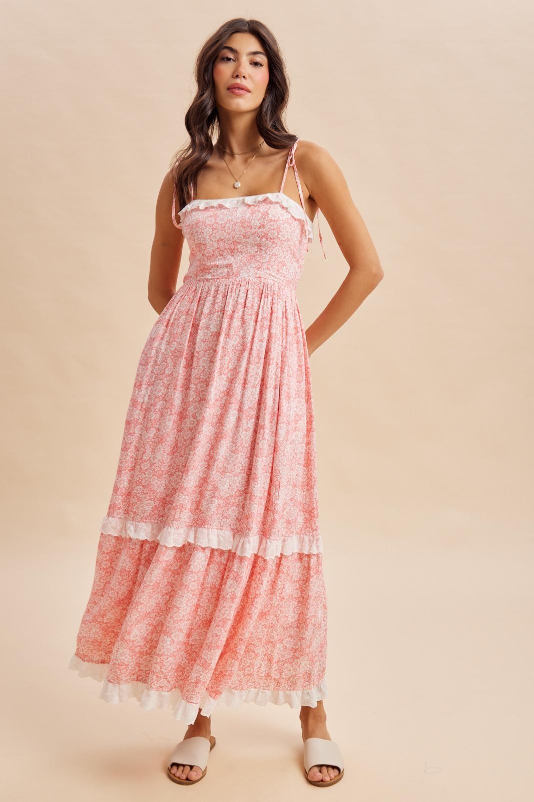 woman wearing a pink floral maxi dress with a fitted bodice and ruffled hemline