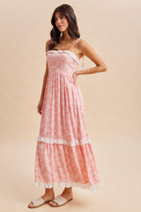 woman wearing a pink floral maxi dress with ruffled accents and adjustable straps