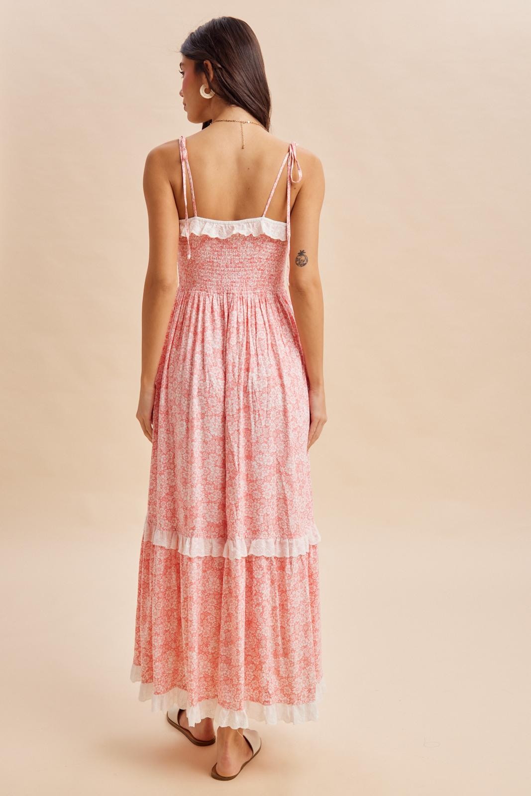 woman wearing a pink floral maxi dress with tiered ruffles and adjustable straps, viewed from the back