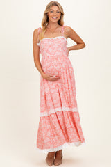 woman wearing a pink floral maternity maxi dress with ruffled straps and holding her baby bump