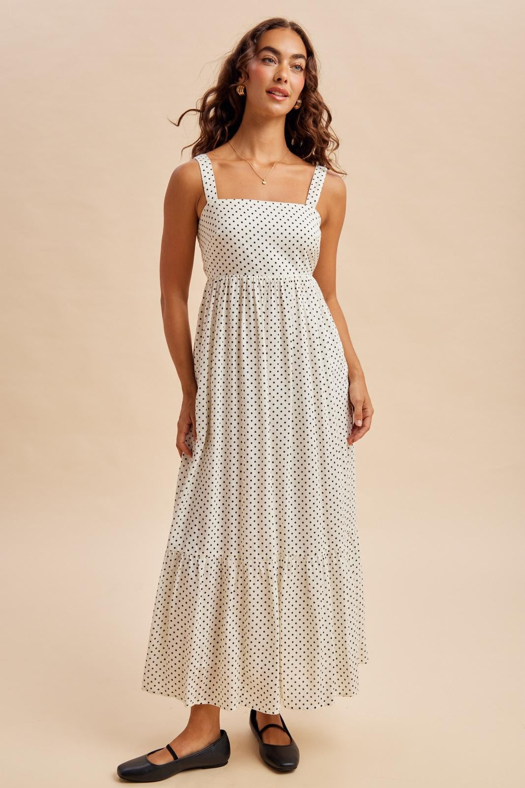 woman wearing a white polka dot maxi dress with a square neckline and tiered skirt, styled with black flats