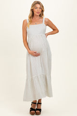 woman wearing a white polka dot maternity maxi dress and holding her baby bump