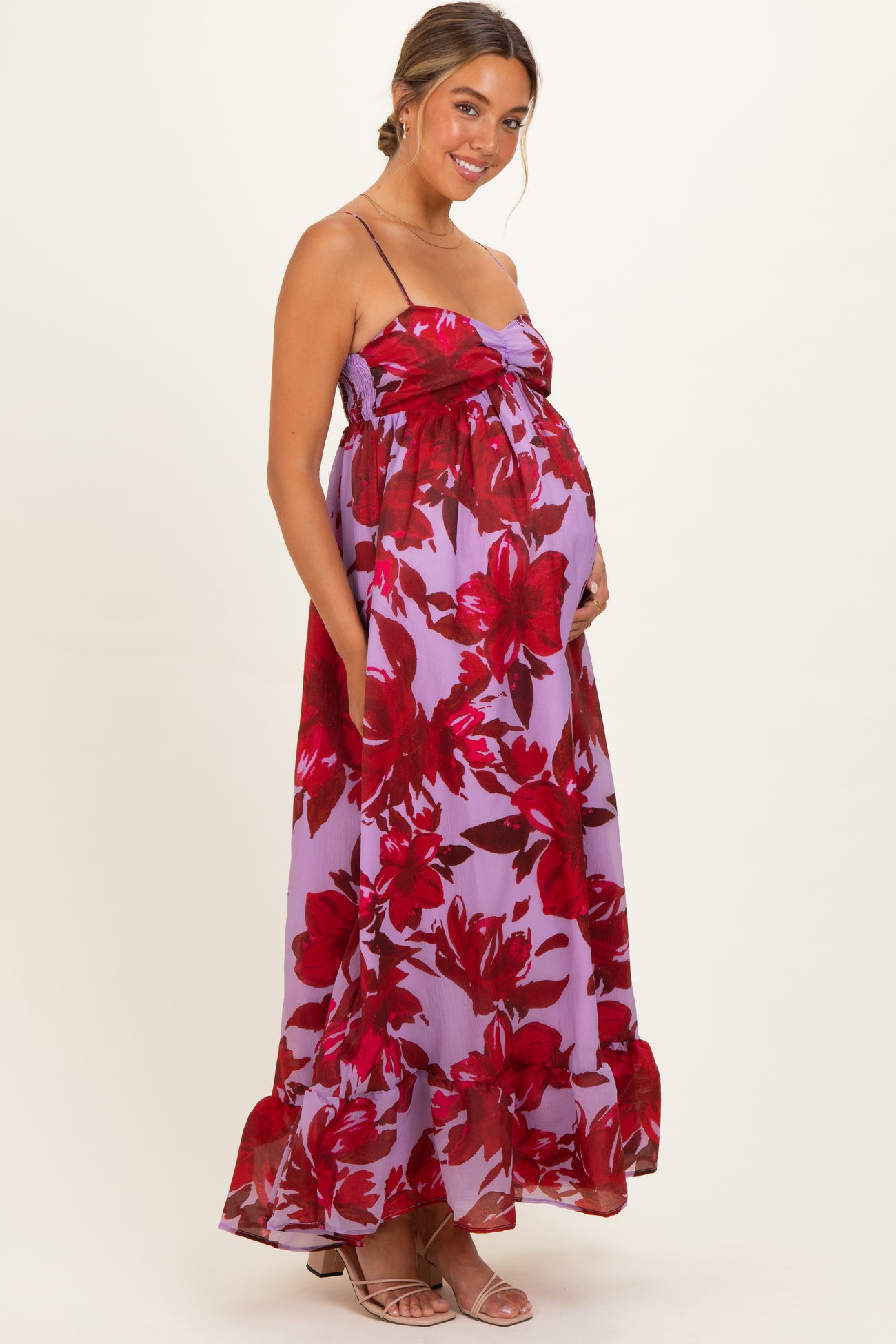 woman wearing a purple floral maternity maxi dress with a knotted bodice and ruffled hem, highlighting her baby bump
