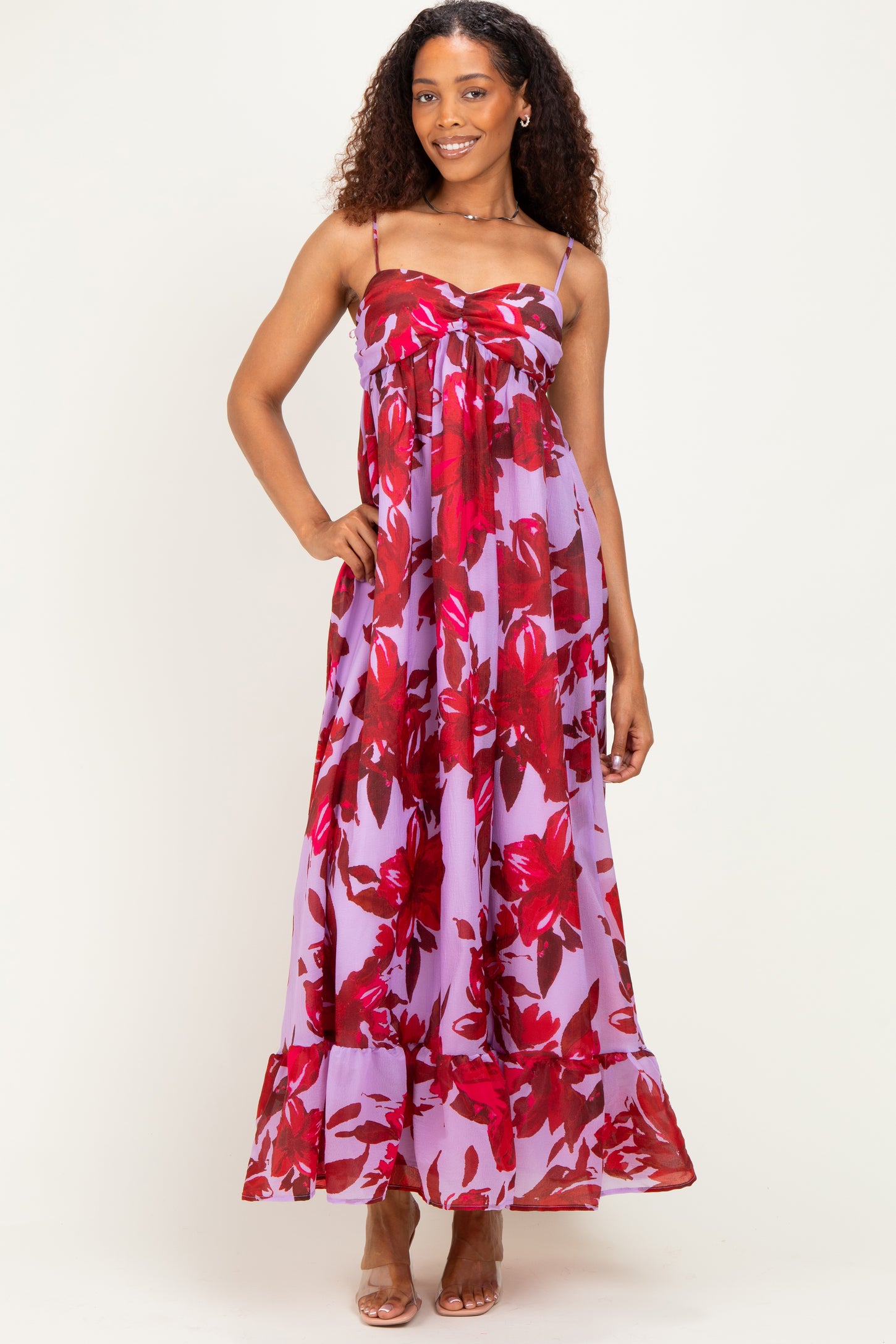 woman wearing a purple maxi dress with red floral prints and spaghetti straps