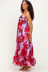 woman wearing a sleeveless purple maxi dress with red floral print and ruffled hem