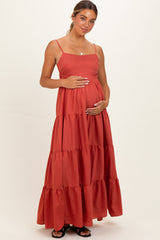 woman wearing a rust-colored tiered maxi maternity dress and holding her baby bump