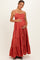 woman wearing a rust-colored tiered maxi maternity dress and holding her baby bump