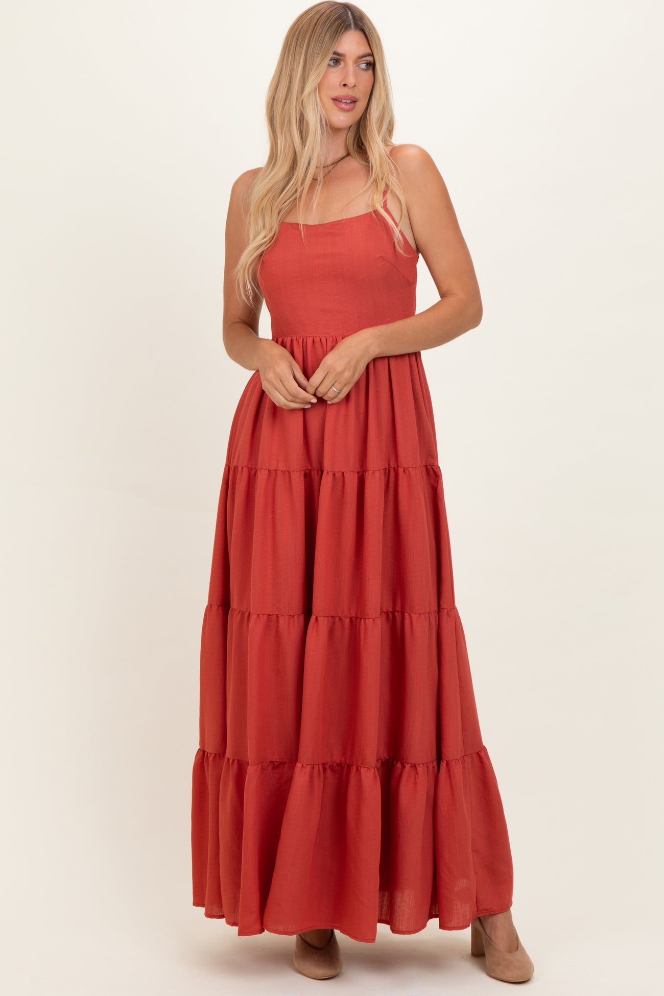 woman wearing a rust red tiered maxi dress with a square neckline and a flowy silhouette
