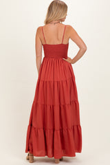 woman wearing a rust red tiered maxi dress with a smocked back and adjustable spaghetti straps