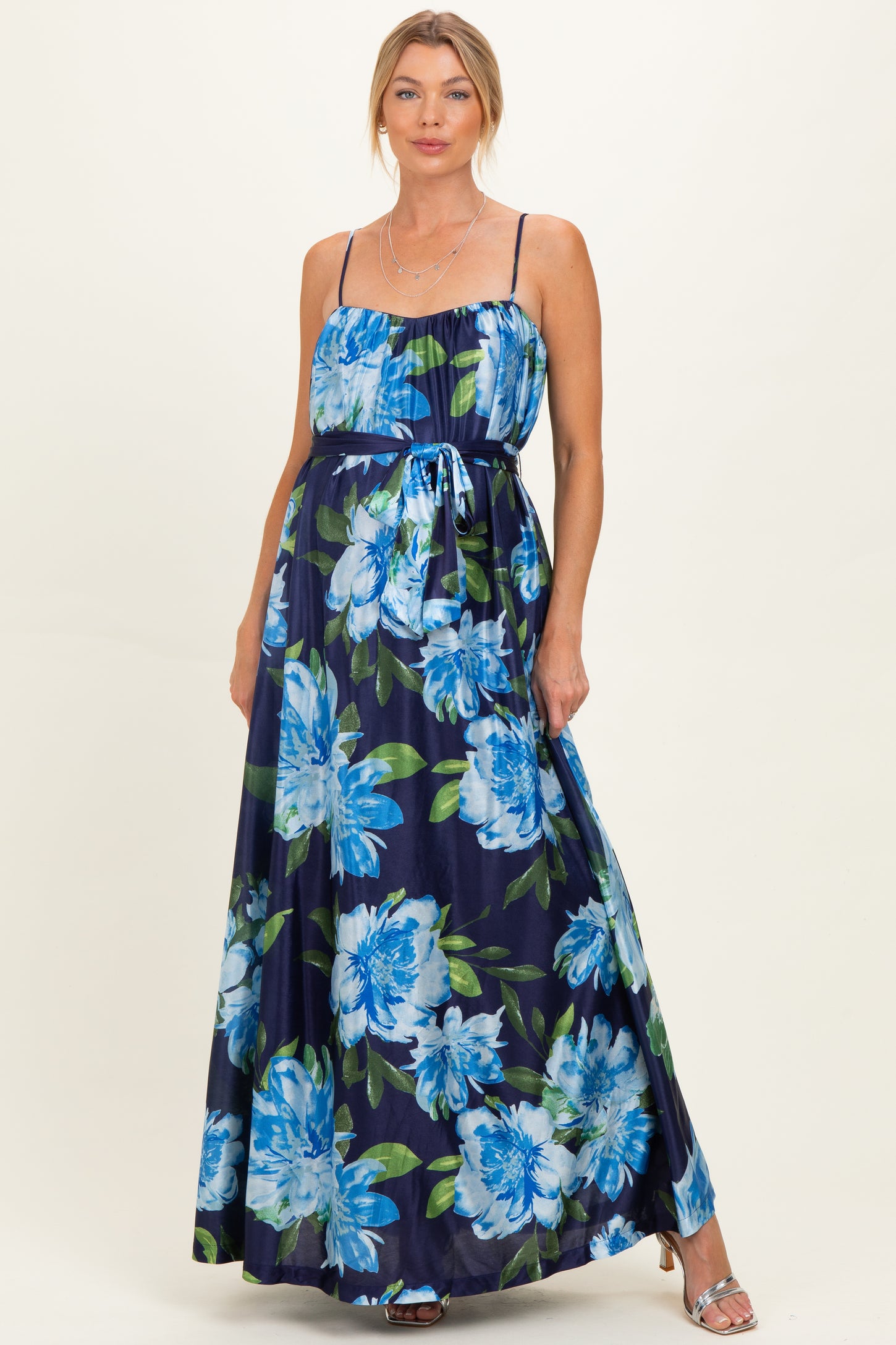 woman wearing a navy floral maternity maxi dress with a cinched waist and spaghetti straps, showcasing a baby bump