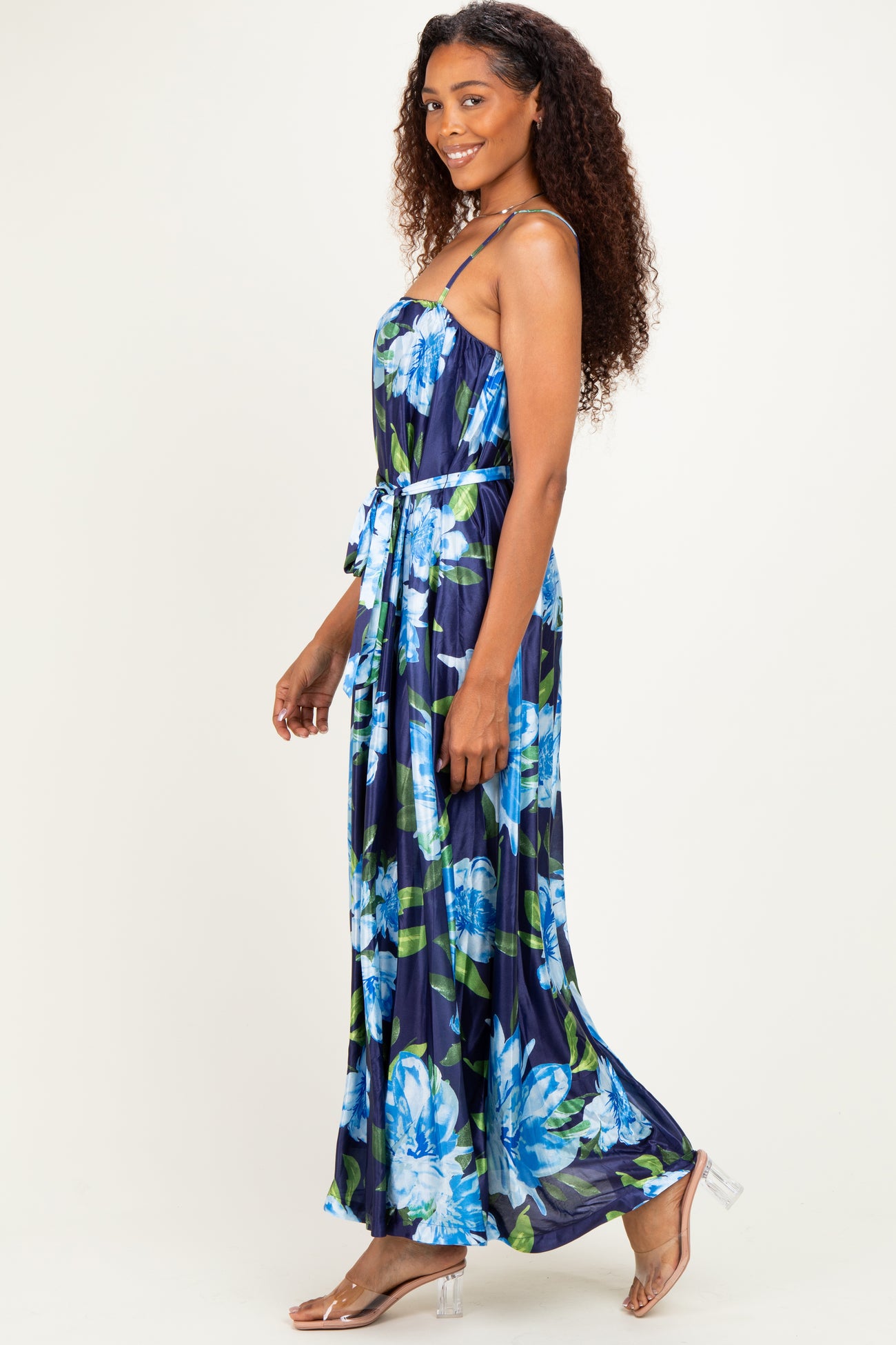 woman wearing a navy blue floral maxi dress with a cinched waist and thin straps, standing sideways