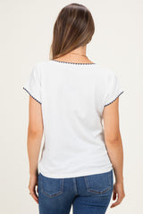 woman wearing a white maternity top with navy trim on the sleeves, seen from the back