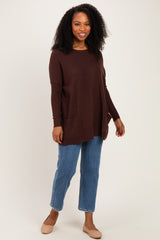 woman wearing a brown long sleeve knit sweater with side pockets and blue straight leg jeans