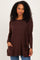 woman wearing a dark brown knit top with side pockets and long sleeves, standing against a light background
