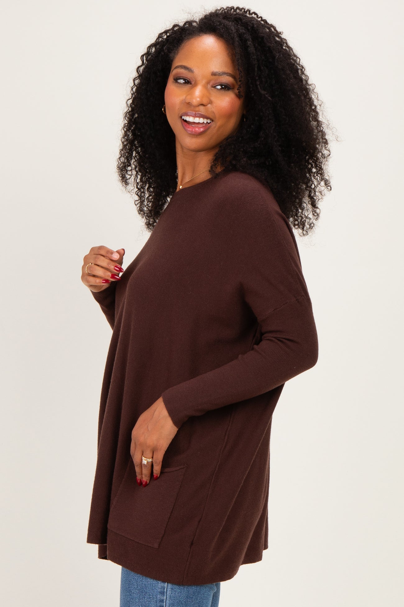 woman wearing a chocolate brown oversized sweater with a front pocket and long sleeves