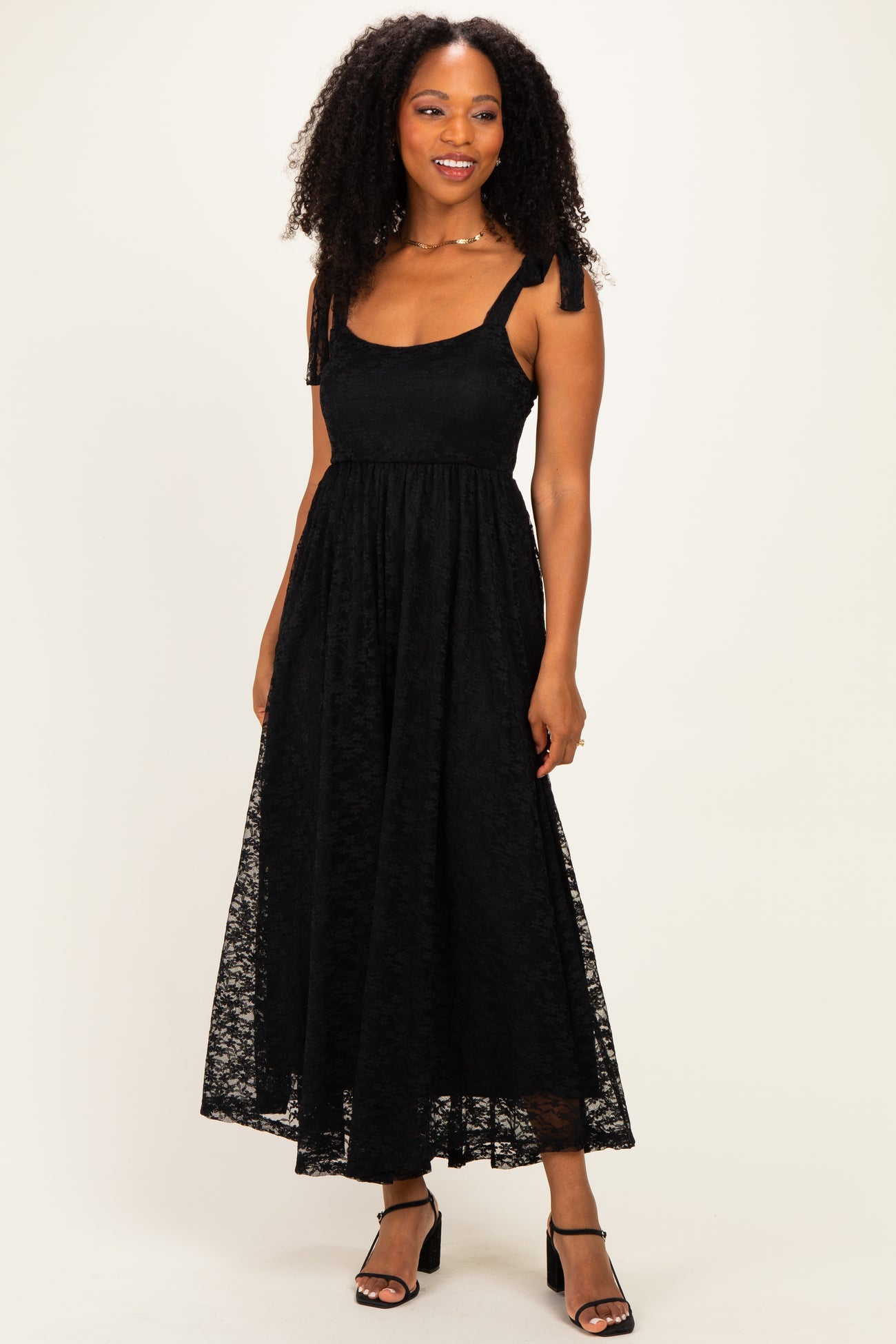woman wearing a black lace maxi dress with tie straps and a flowy hemline