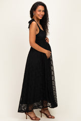 woman wearing a black lace maternity dress with tie straps and a visible baby bump