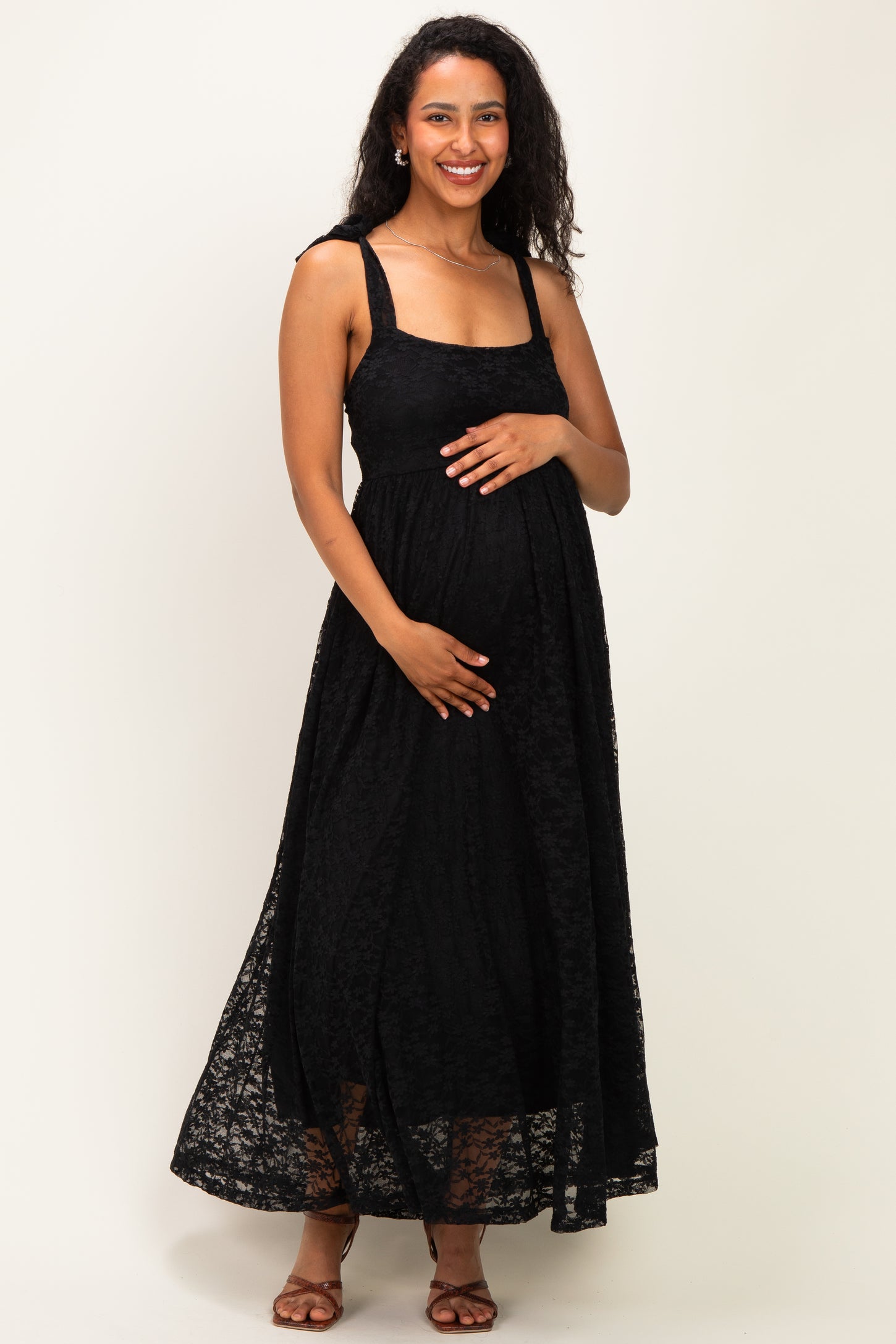 woman wearing a black lace maternity maxi dress and holding her baby bump