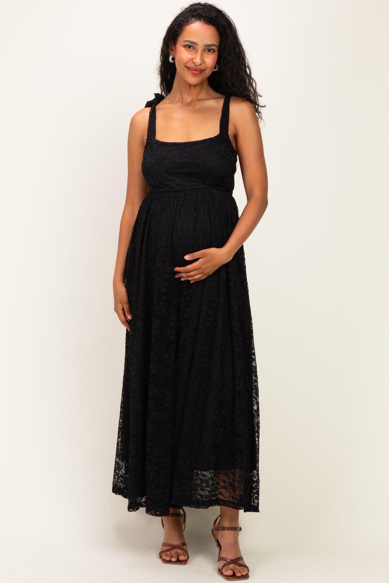woman wearing a black lace maternity maxi dress and holding her baby bump