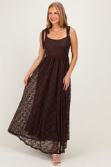 woman wearing a brown lace maxi dress with tie shoulder straps and a flowy skirt