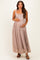 woman wearing a light pink lace maternity maxi dress and gently holding her baby bump