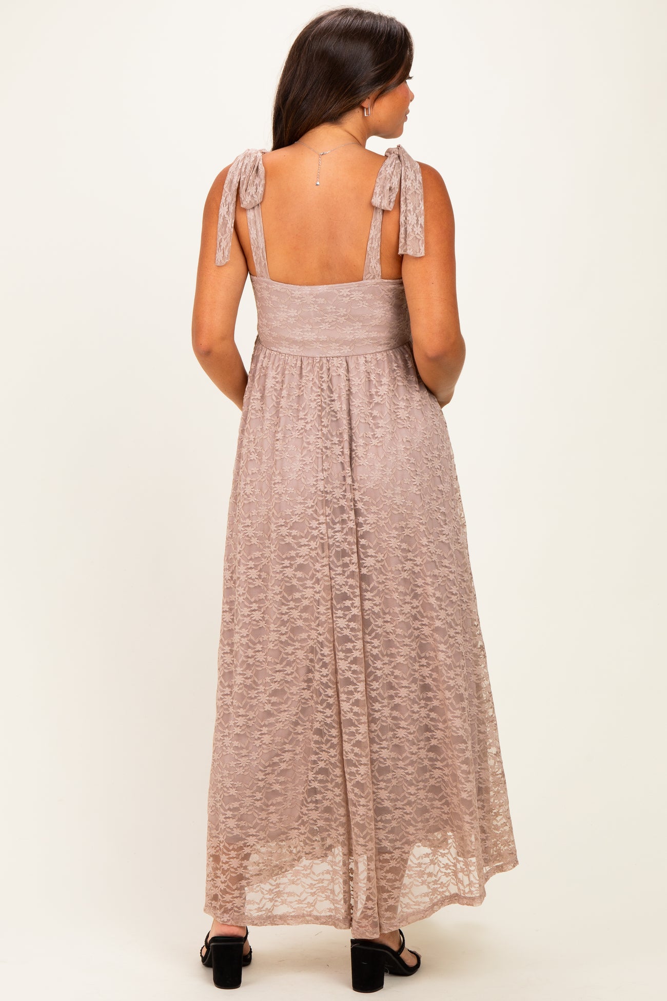 woman wearing a light pink maternity maxi dress with tie straps and a fitted bodice, showing a subtle lace texture