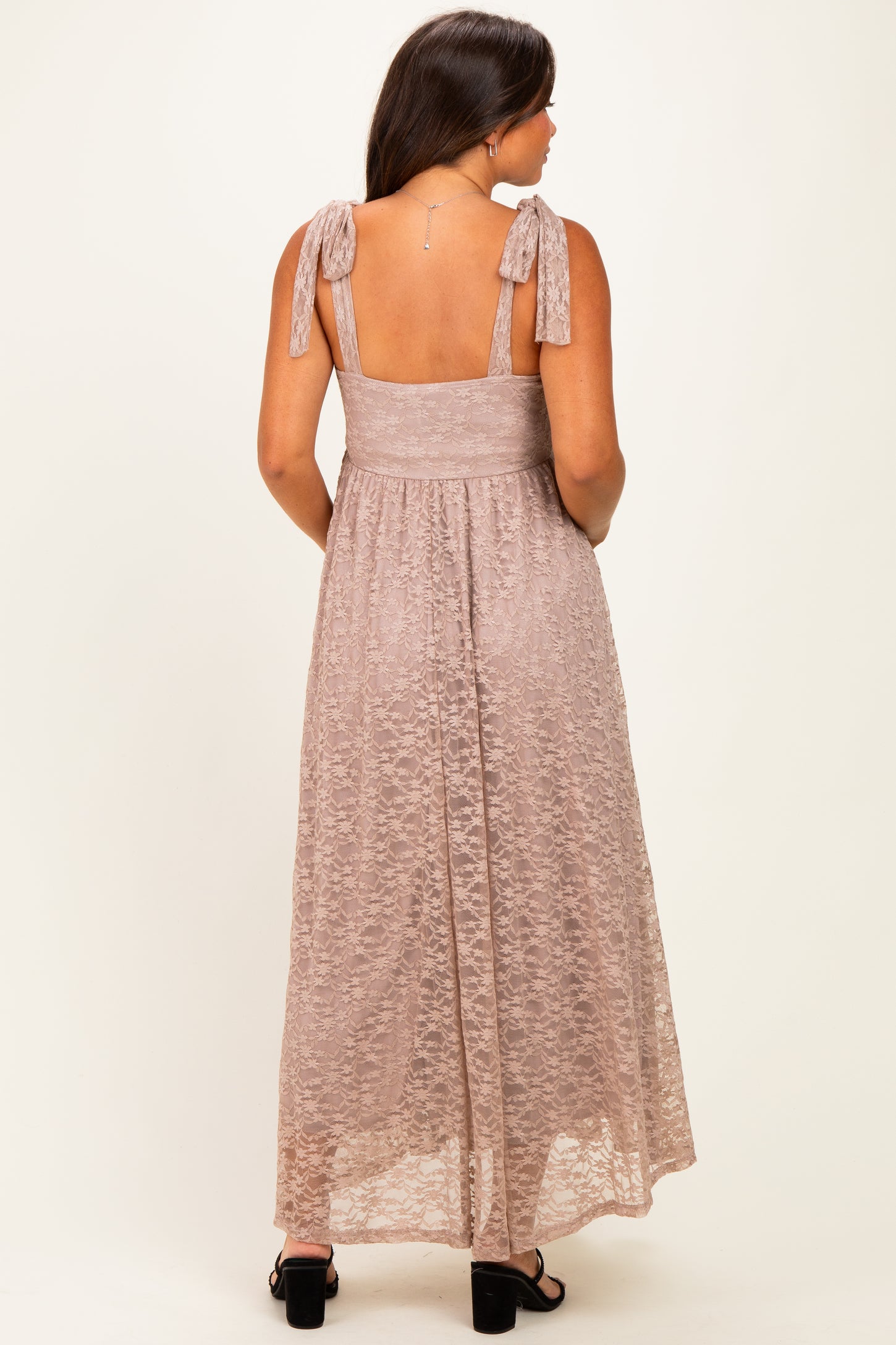 woman wearing a light pink maternity maxi dress with tie straps and a fitted bodice, showing a subtle lace texture