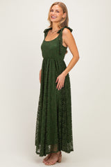 woman wearing a dark green lace maxi dress with tie straps and a fitted waist, smiling at the camera