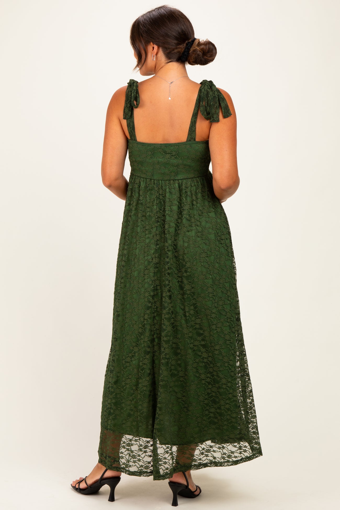 woman wearing a dark green lace maternity maxi dress with tie straps and a flowing skirt