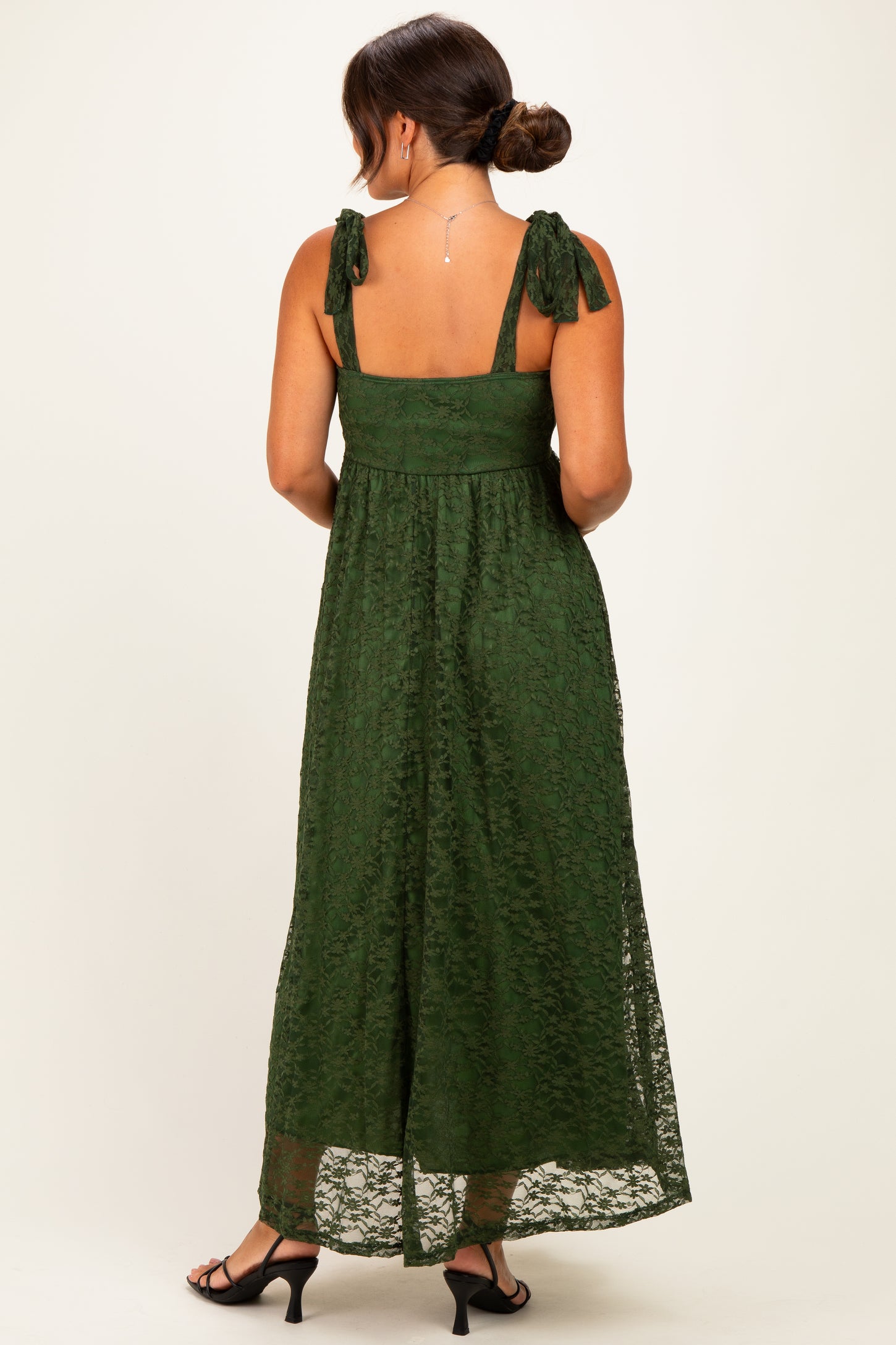woman wearing a dark green lace maternity maxi dress with tie straps and a flowing skirt