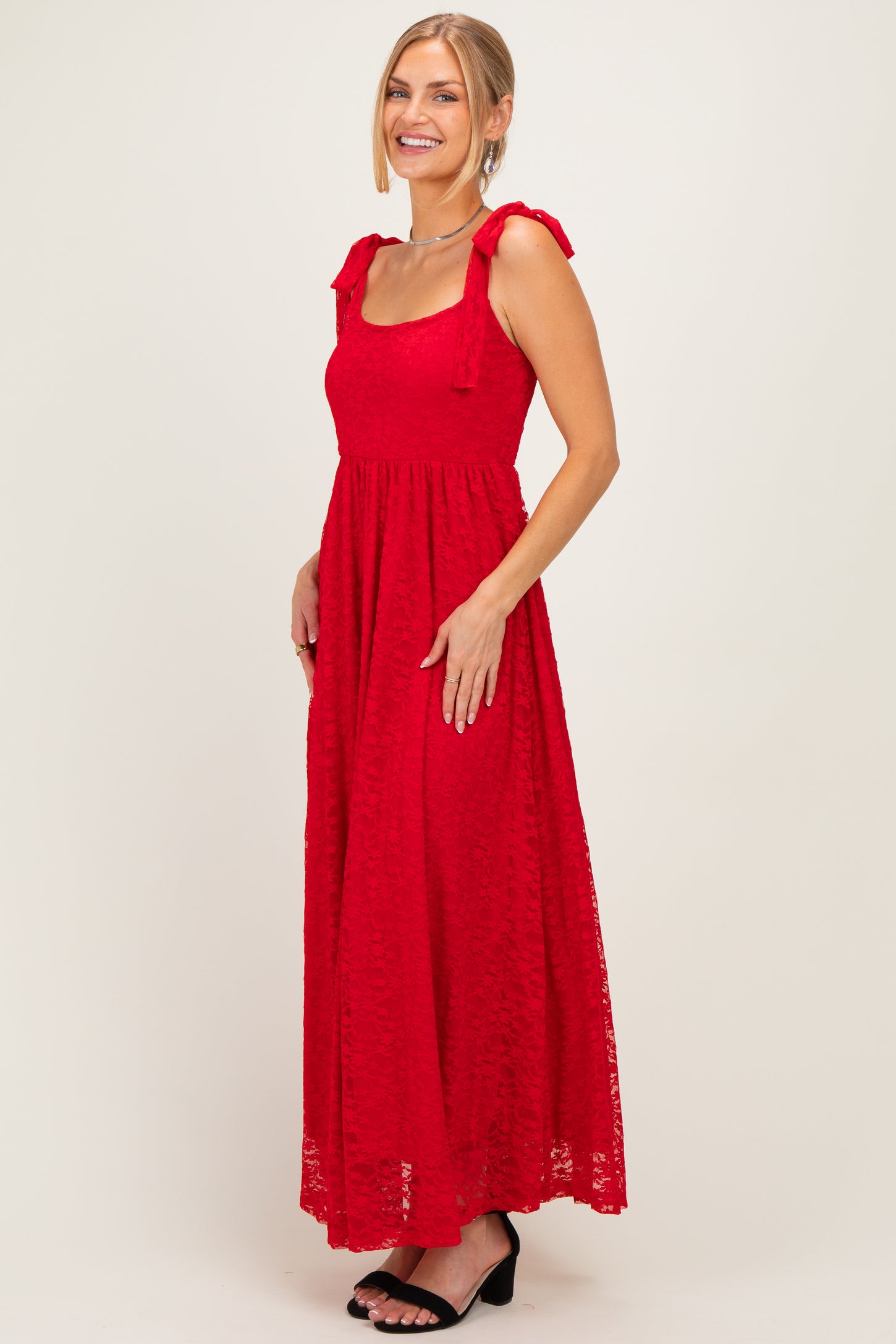 woman wearing a red maxi dress with bow-tie shoulder straps and a fitted bodice