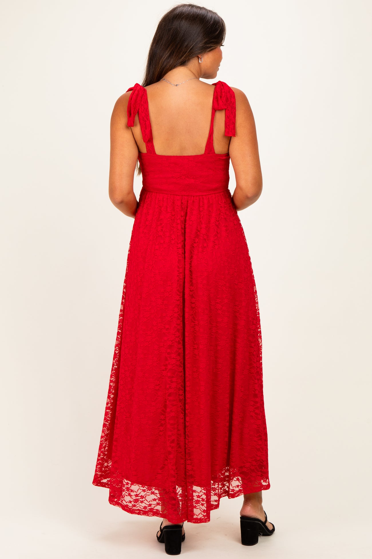 woman wearing a red lace maternity maxi dress with tie shoulder straps, showing a baby bump from the back