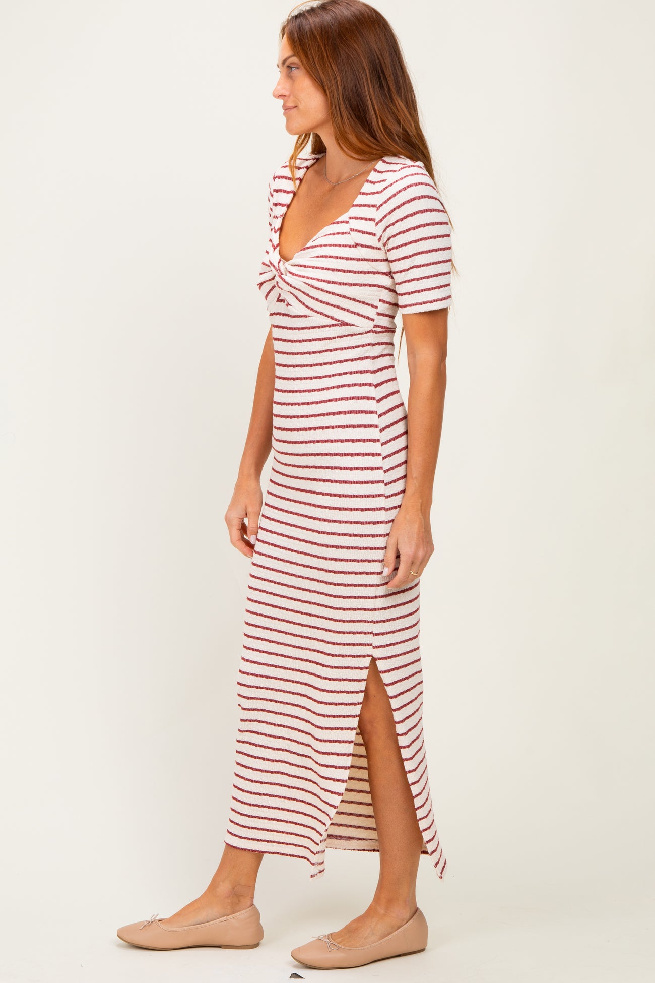 woman wearing a striped midi dress with a knotted front and side slit, paired with flat shoes