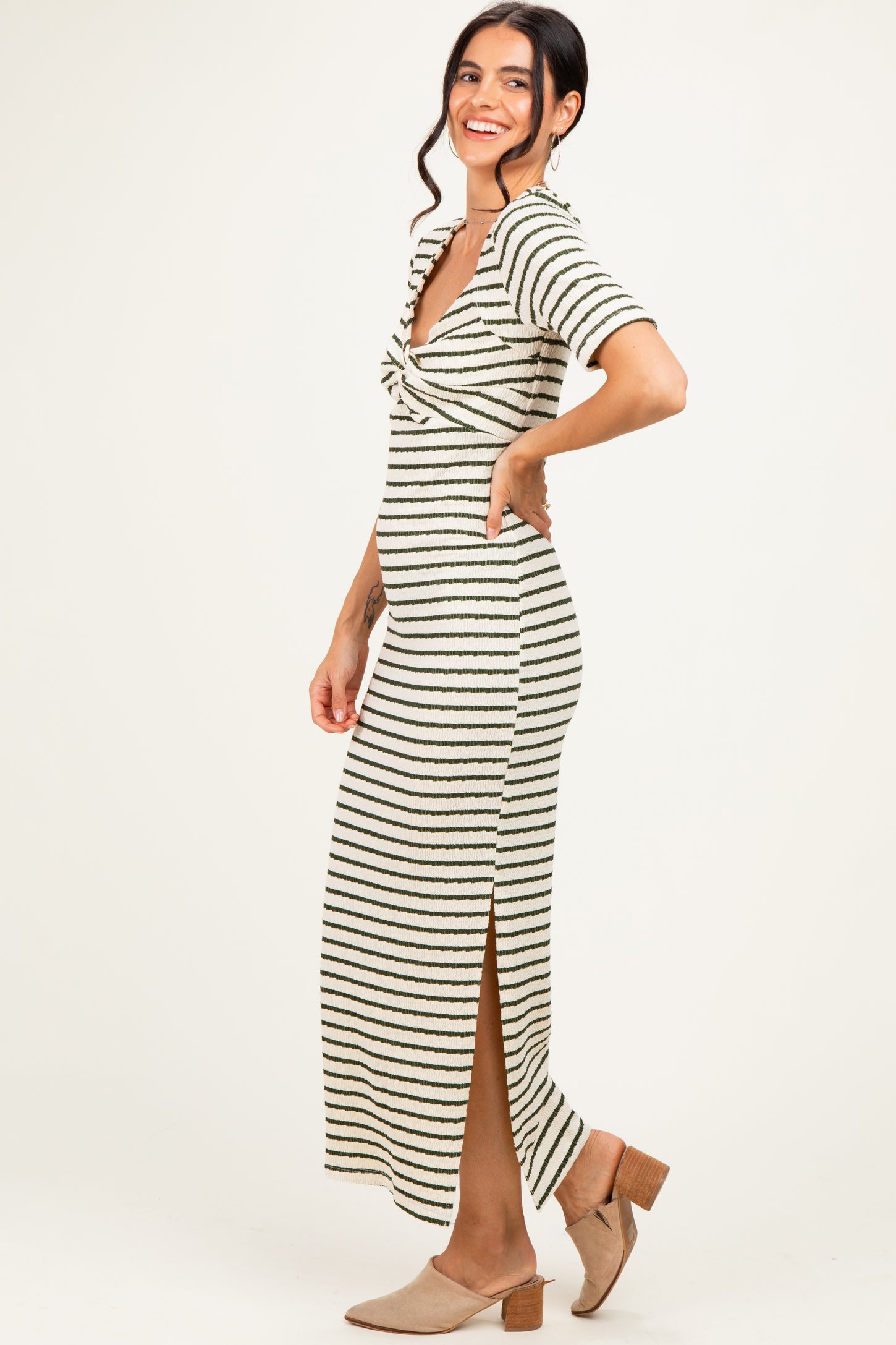 woman wearing a striped midi dress with a twist front and side slits, styled with beige heels