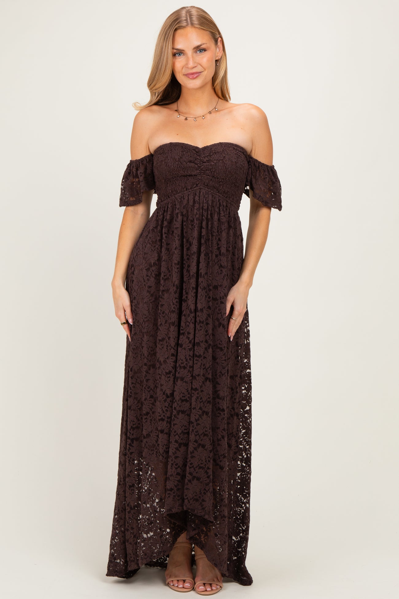 woman wearing a brown off-the-shoulder lace maxi dress with a fitted bodice and flowing skirt
