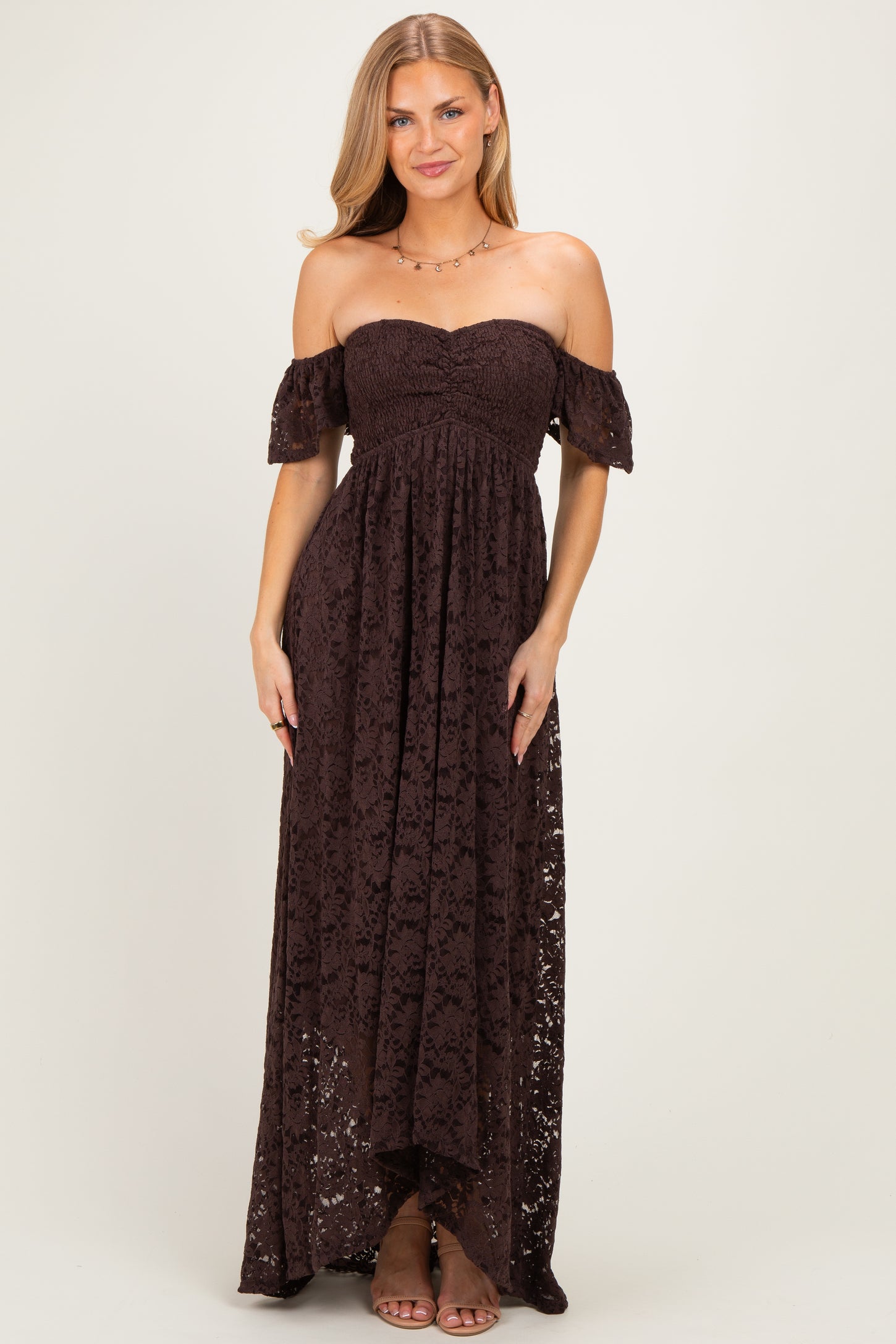 woman wearing a brown off-the-shoulder lace maxi dress with a fitted bodice and flowing skirt