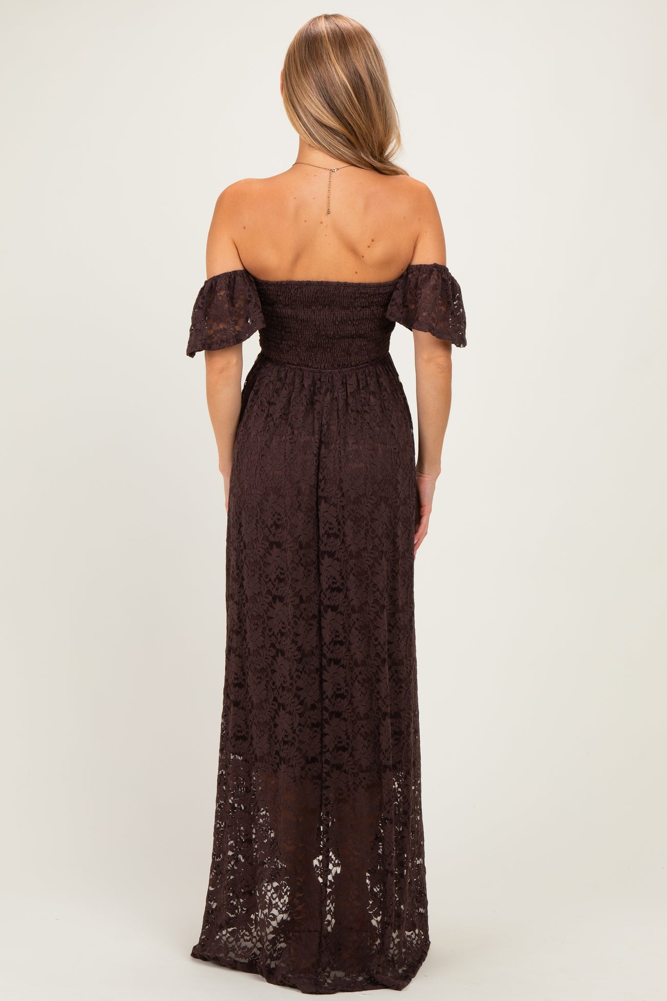 woman wearing a dark brown off-the-shoulder maxi dress with lace details and short puff sleeves, shown from the back