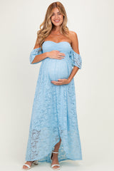 woman wearing a light blue off-the-shoulder maternity maxi dress, showcasing her baby bump