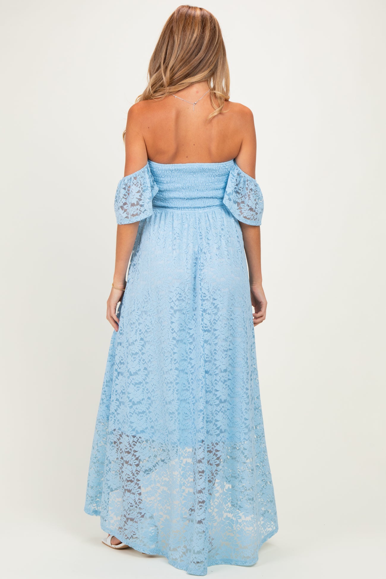 woman wearing a light blue lace off-shoulder maternity dress with puff sleeves and a flowing maxi length